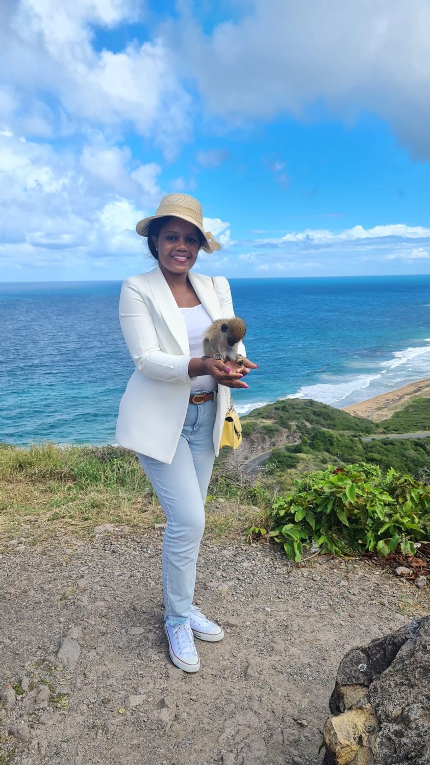Kadine Reynolds holding a monkey on a cliffside, St. Kitts